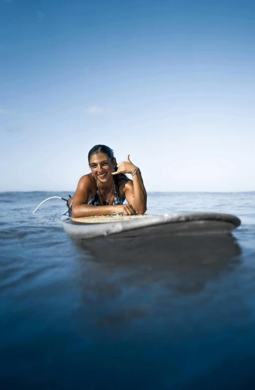 a woman laying on top of a surfboard in the ocean, smiling for the camera, profile image, slide show, close-up photograph