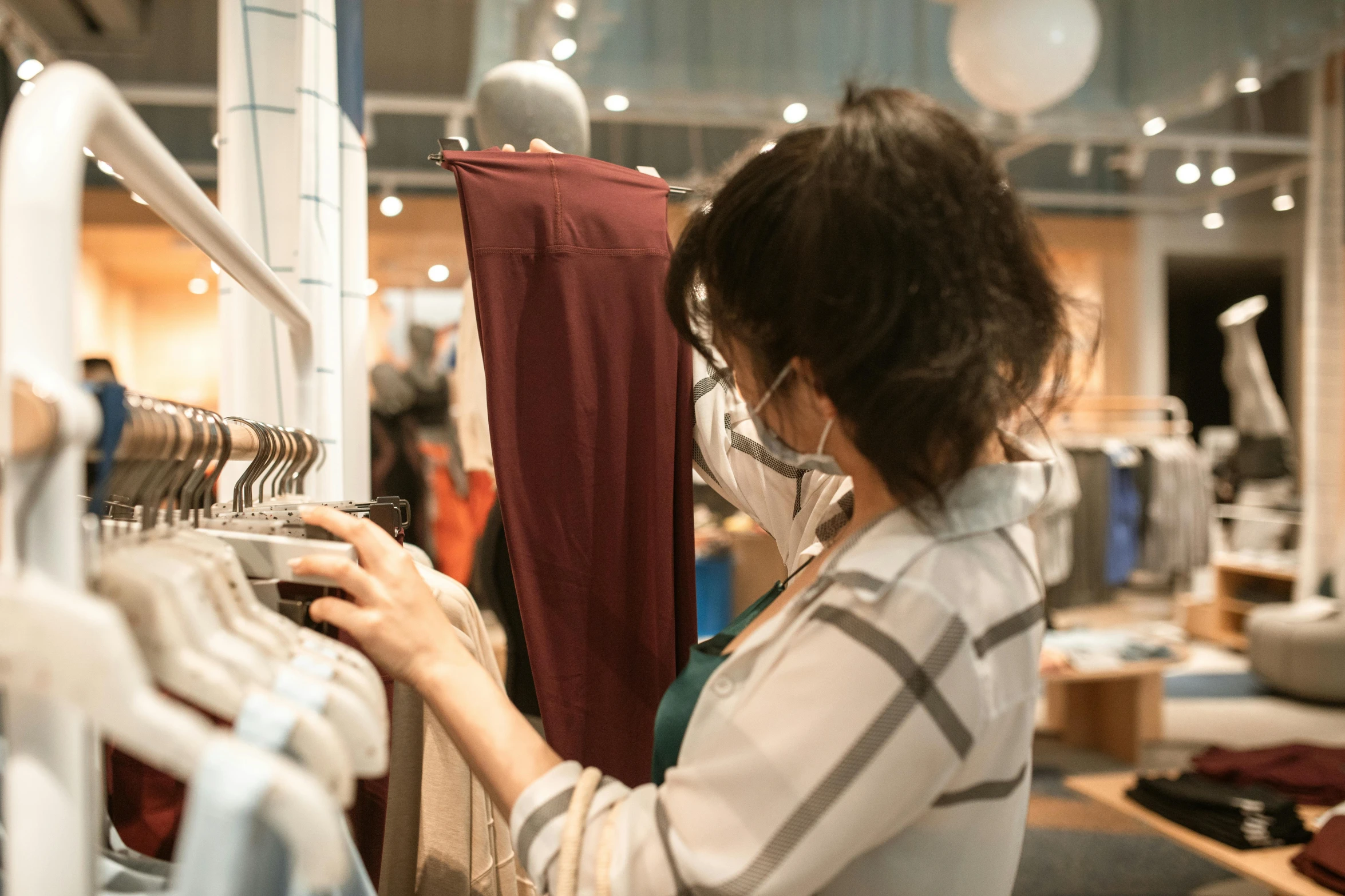 a woman wearing a face mask in a clothing store, trending on pexels, happening, pants, wearing a brown cape, inspect in inventory image, thumbnail