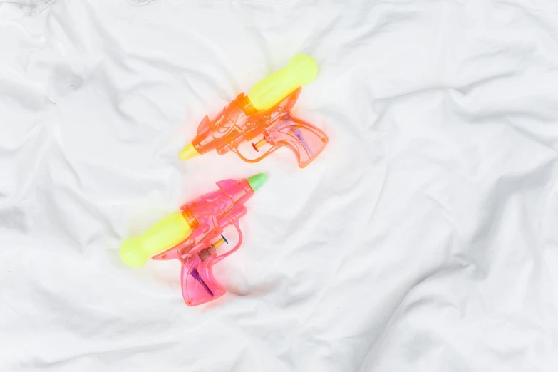 a couple of water guns laying on top of a bed, unsplash, white neon wash, flat lay, detail shot, ready to eat