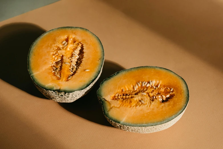 a couple of melons sitting on top of a table, by Carey Morris, unsplash, hurufiyya, ochre, background image, open belly, close-up product photo