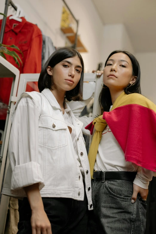 two women standing next to each other in a room, by Olivia Peguero, trending on pexels, gutai group, wearing a barca cape, wearing a shirt and a jean, wearing red and yellow clothes, ripped up white garment