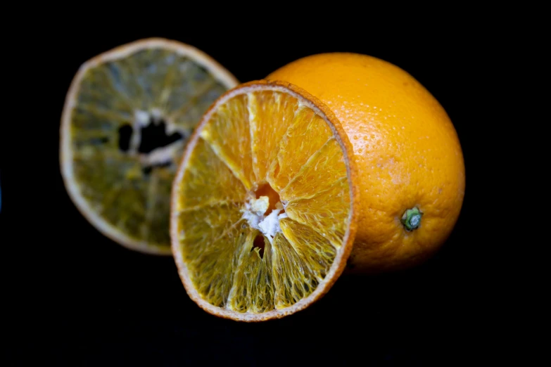 two oranges cut in half on a black background, a macro photograph, by Jesper Knudsen, pexels, fan favorite, mixed art, dead fruits, medium format