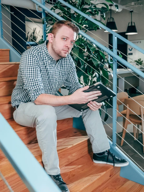 a man sitting on a set of stairs using a laptop, by Adam Marczyński, happening, confident stance, low quality photo, rectangle, volodymyr zelenskyy
