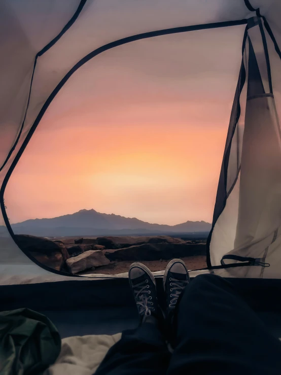 a person sitting inside of a tent at sunset, profile image