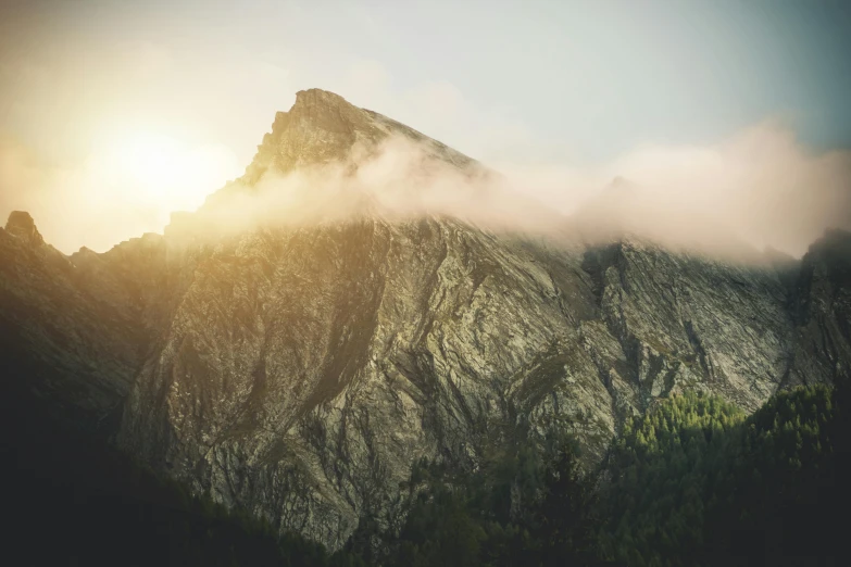 the sun shines through the clouds on top of a mountain, by Sebastian Spreng, pexels contest winner, dusty rock in background, soft light misty, multiple stories, brown