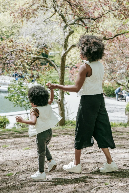 a woman and a child playing frisbee in a park, by Nina Hamnett, trending on unsplash, happening, kara walker james jean, pants, white, nyc