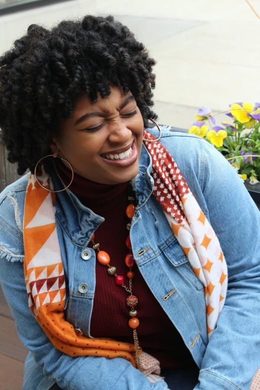a woman sitting on a bench next to a potted plant, by Lily Delissa Joseph, happening, patterned scarf, earing a shirt laughing, orange and brown leaves for hair, wearing a turtleneck and jacket