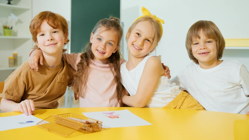a group of children sitting around a yellow table