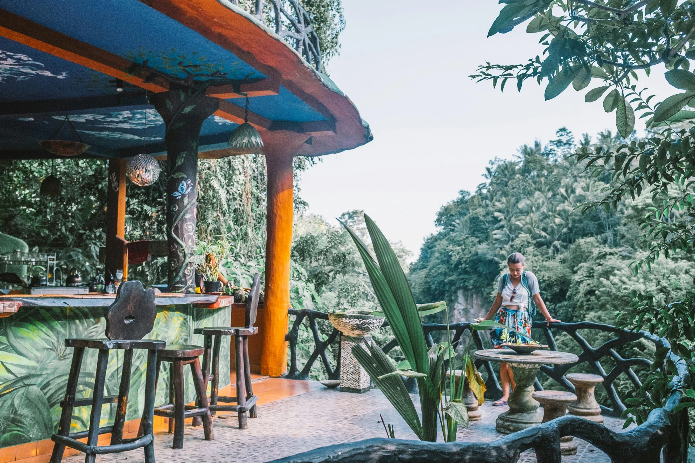 a man standing in front of a bar with stools, by Daniel Lieske, unsplash, sumatraism, floral jungle treehouse, panorama view, breakfast at las pozas, avatar image