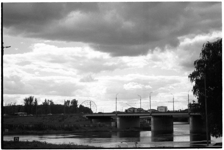 a black and white photo of a bridge over a river, by Maurycy Gottlieb, flickr, round clouds, winnipeg skyline, magical soviet town, 3 5 mm digital photo