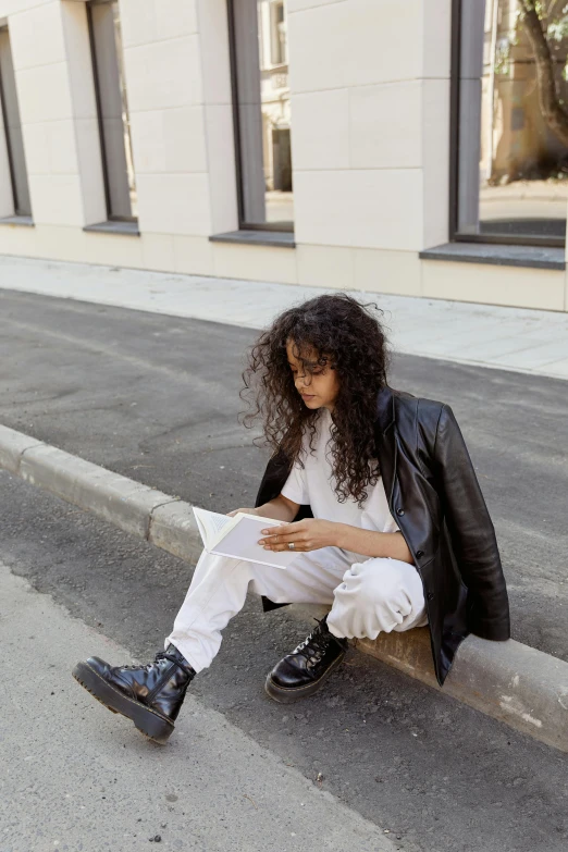 a woman sitting on a curb reading a book, by Christen Dalsgaard, happening, black long curly hair, white and black clothing, streetwear, white soft leather model