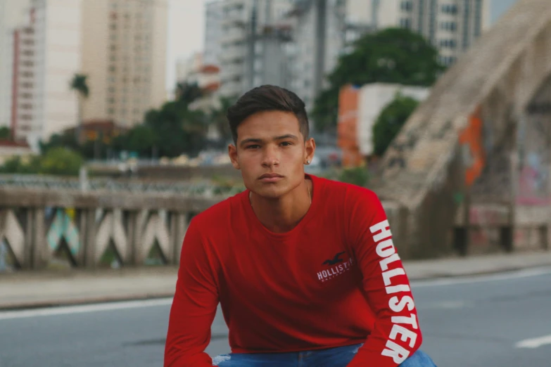 a man in a red shirt is sitting on a skateboard, inspired by Nathan Oliveira, instagram, official store photo, long sleeve, huleeb, headshot profile picture