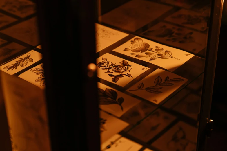 a group of cards sitting on top of a tiled floor, an etching, trending on unsplash, visual art, back lit lighting, body covered in floral tattoos, inside in a glass box, detail studio quality lighting