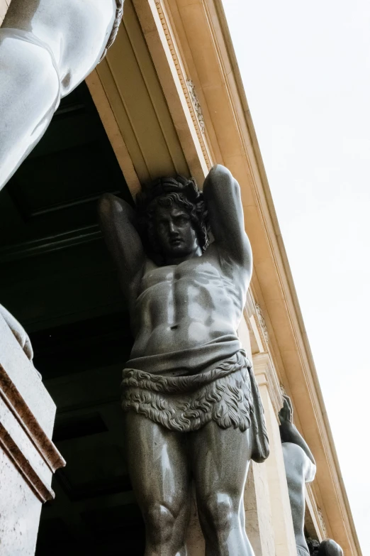 a statue of a man hanging from the side of a building, up-close, hercules, best photo