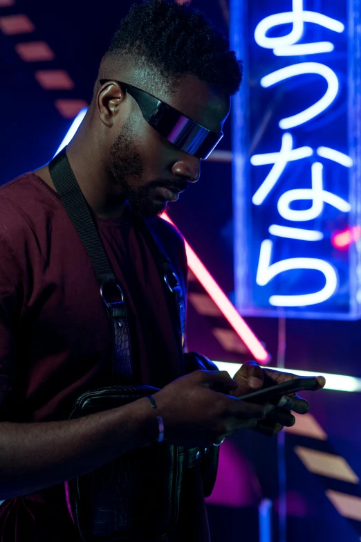 a man holding a cell phone in front of a neon sign, pexels, afrofuturism, [ theatrical ], cyber goggles, yasuke 5 0 0 px models, dj at a party