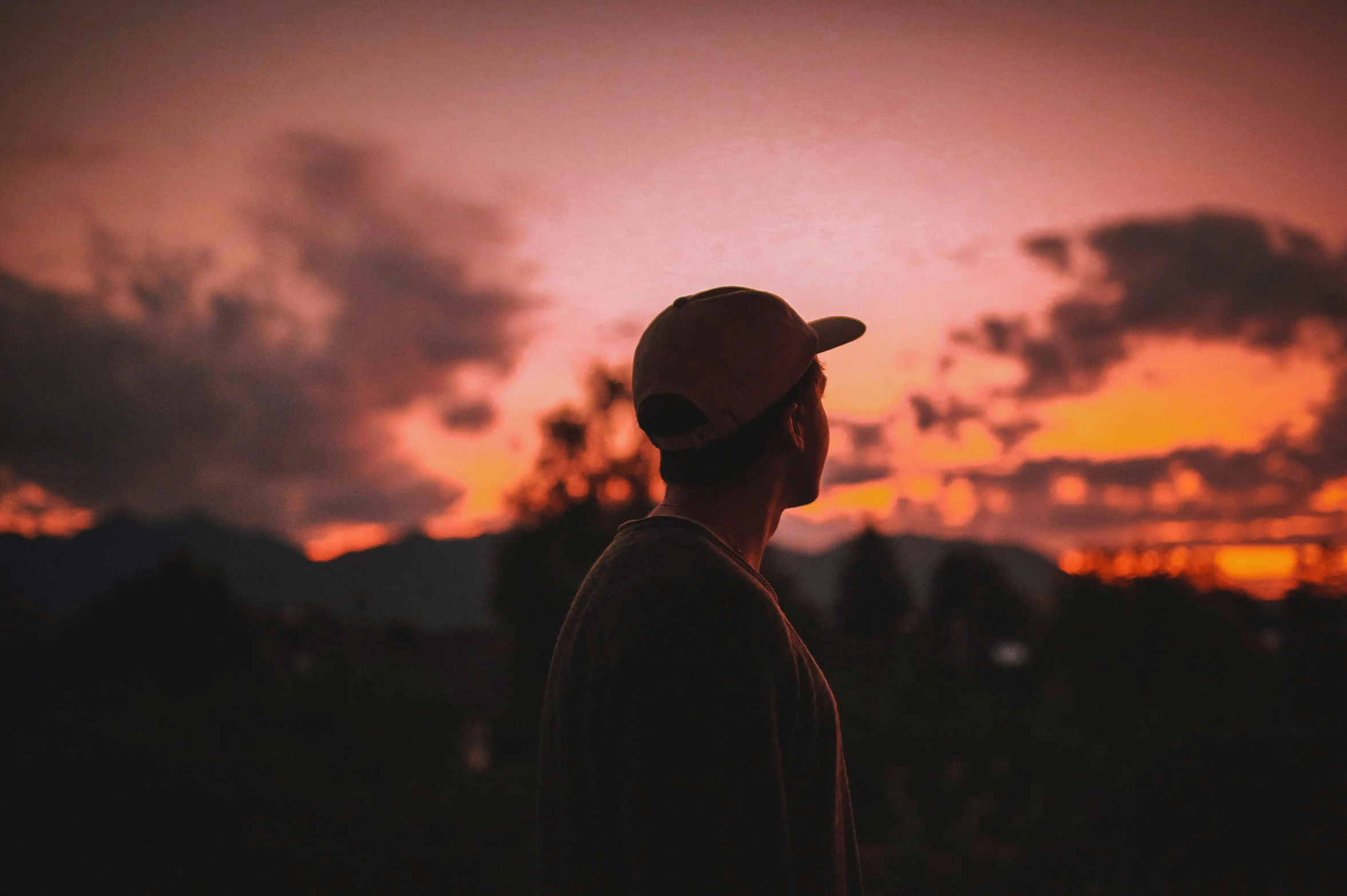 a man standing in front of a sunset, pexels contest winner, wearing a backwards baseball cap, profile pic, lo fi colors, beautiful surroundings