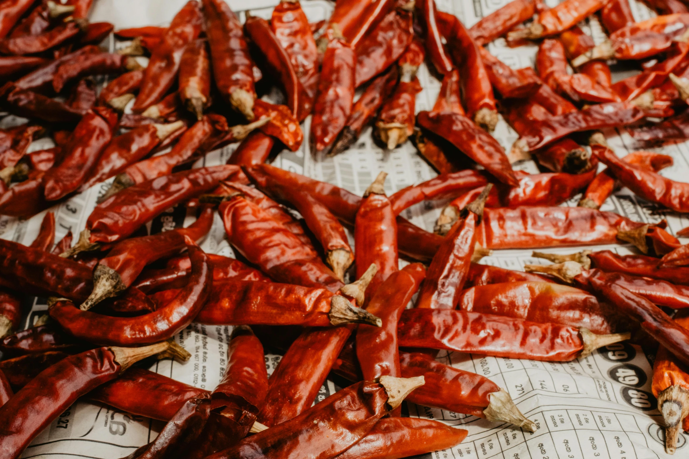 a pile of red peppers sitting on top of a newspaper, by Daniel Lieske, pexels, process art, sichuan, 🦩🪐🐞👩🏻🦳, background image, spicy