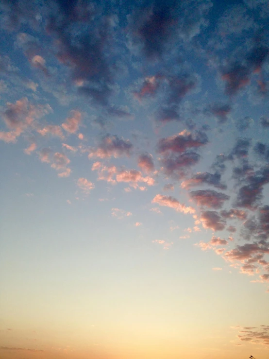 a man riding a surfboard on top of a sandy beach, a picture, unsplash, aestheticism, pink clouds in the sky, tall fluffy clouds, ((sunset)), aesthetic clouds in the sky