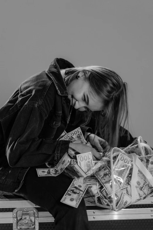 a woman sitting on top of a suitcase filled with money, a black and white photo, by Niko Henrichon, pexels contest winner, girl wearing hoodie, ((messy)), piled around, yung lean