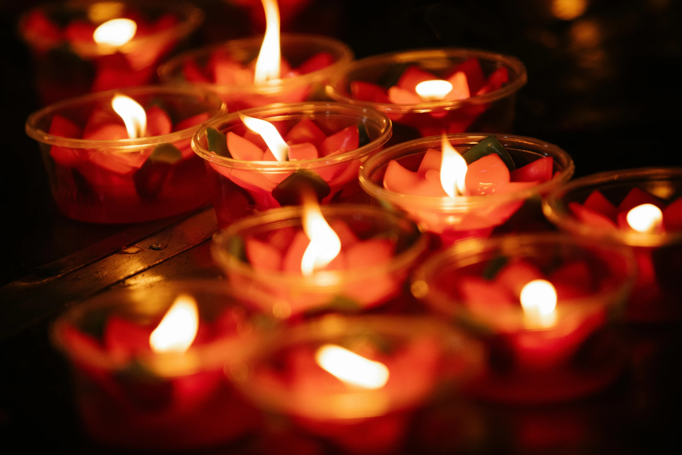 a group of lit candles sitting on top of a table, lotuses, glowing red, bright and moody, a brightly coloured