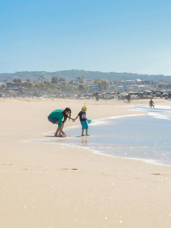 a couple of people standing on top of a sandy beach, on the sand