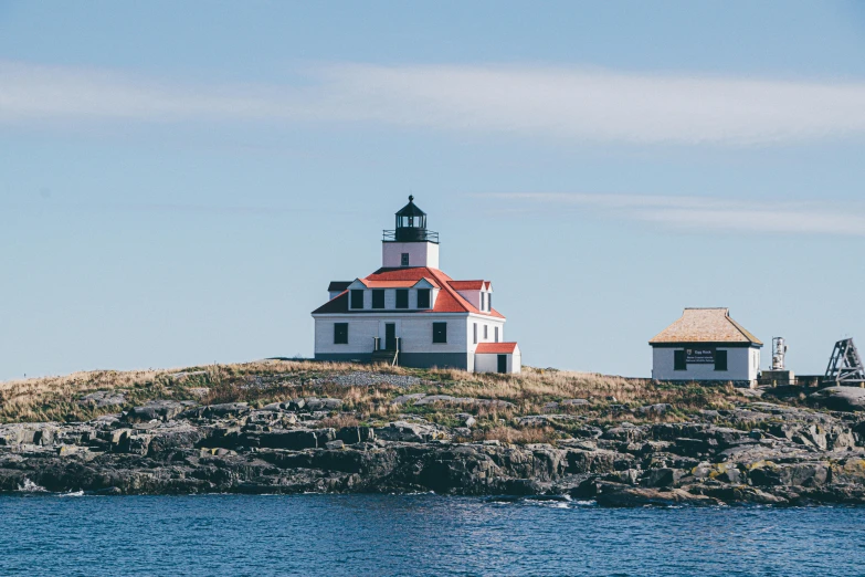 a lighthouse sitting on top of a rocky island, by Carey Morris, pexels contest winner, new england architecture, 1970s photo, 🚿🗝📝