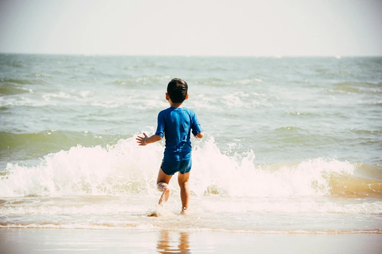 a little boy that is standing in the water, by Arabella Rankin, pexels contest winner, coming out of the ocean, blue print, cardboard, running freely