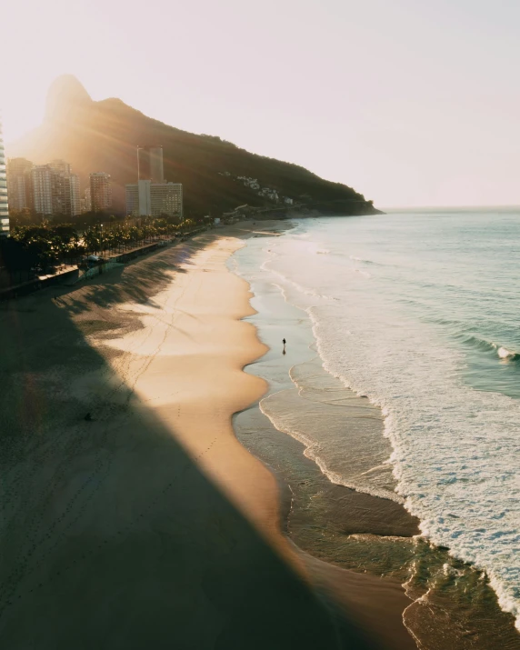 a man riding a surfboard on top of a sandy beach, by Elsa Bleda, pexels contest winner, realism, sun and shadow over a city, rio de janeiro, flatlay, gif