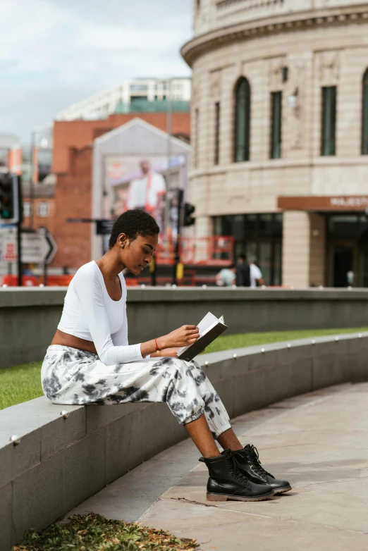 a woman sitting on a wall reading a book, by Alice Mason, trending on unsplash, academic art, coventry city centre, portrait of ororo munroe, square, manchester