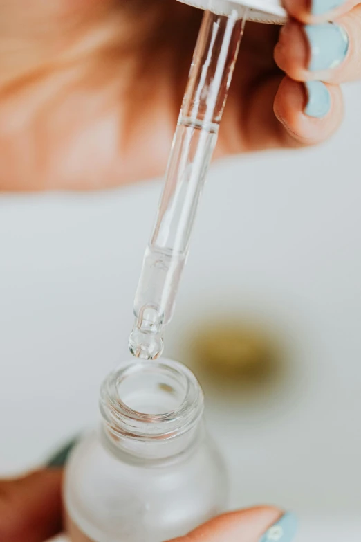 a close up of a person holding a bottle of liquid, by Jessie Algie, syringe, on clear background, creating a soft, handcrafted