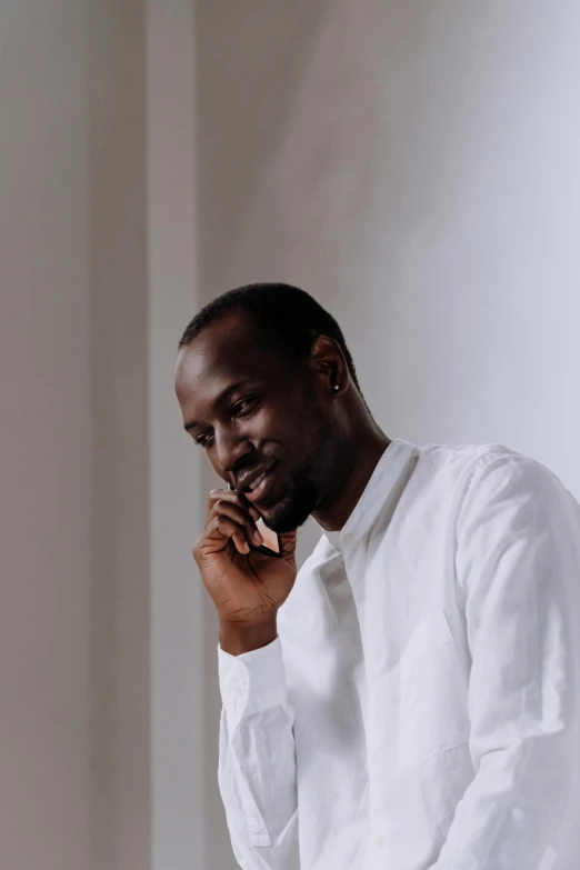 a man in a white shirt talking on a cell phone, inspired by Theo Constanté, pexels contest winner, les nabis, looking off to the side, kevin garnett, wearing white silk, large)}]