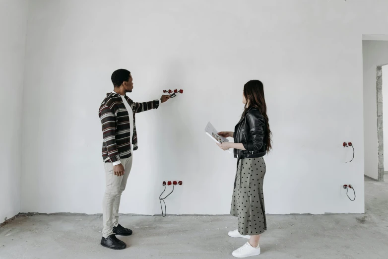 a man and woman standing in an empty room, interactive art, holding a stuff, on a gray background, shooting, wall art