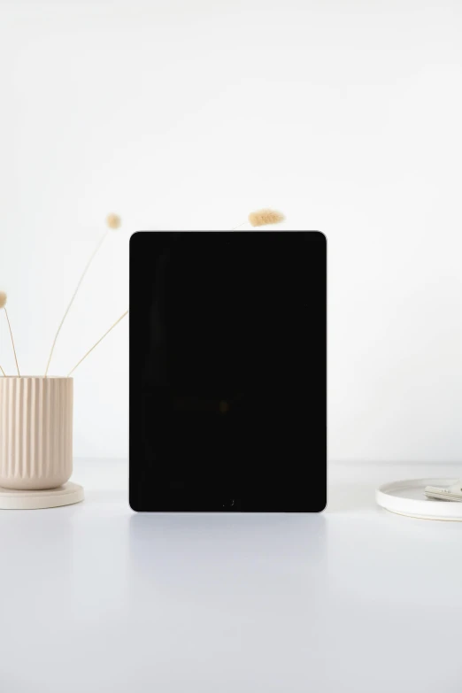 a tablet computer sitting on top of a white table, by Robbie Trevino, minimalism, matte black paper, minimalist sticker, enamel, product introduction photo