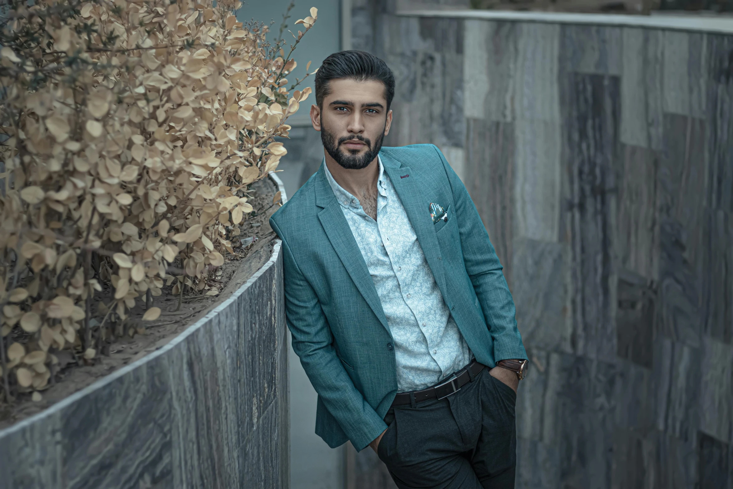 a man in a suit leaning against a wall, a colorized photo, by Ismail Acar, pexels contest winner, white and teal garment, attractive face and body, kyza saleem, wearing elegant casual clothes