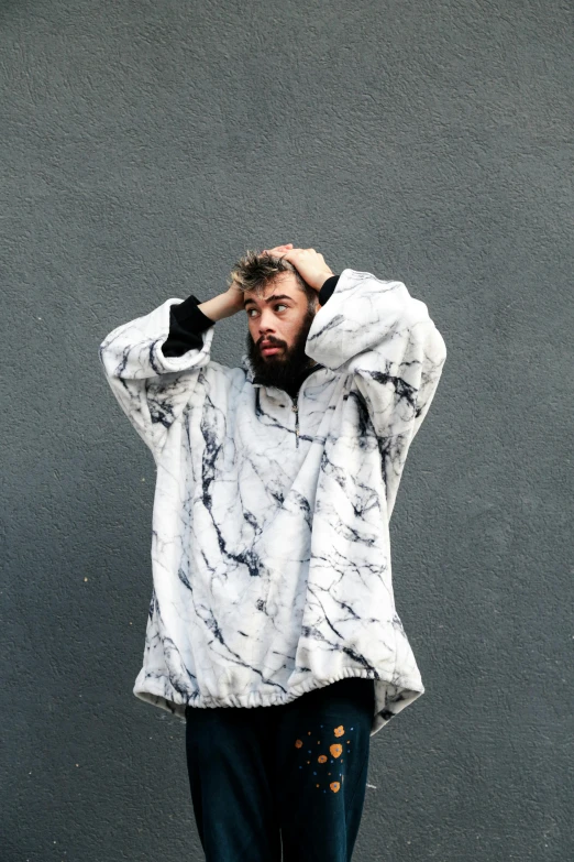 a man standing in front of a gray wall, an album cover, inspired by Alessandro Allori, unsplash, wearing a baggy pajamas, ivory and black marble, covered in matted fur, wearing a white sweater