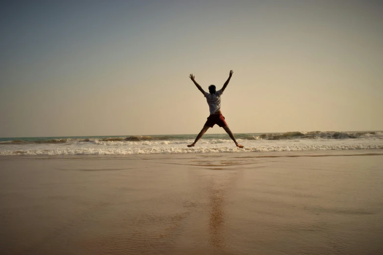 a person jumping in the air on a beach, pexels contest winner, arabesque, vinayak, poor quality, happy toes, low quality photo