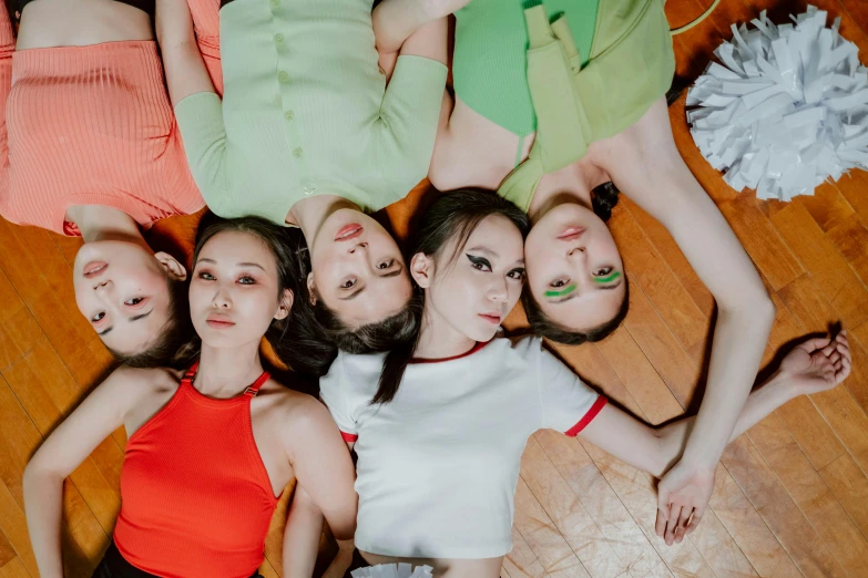 a group of women laying on top of a wooden floor, an album cover, trending on pexels, gutai group, avatar image, jingna zhang, green clothes, birdeye