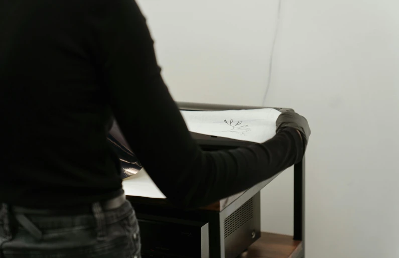 a man that is standing in front of a desk, a silk screen, hand controlling, close up to the screen, drawn on white parchment paper, photograph of a techwear woman