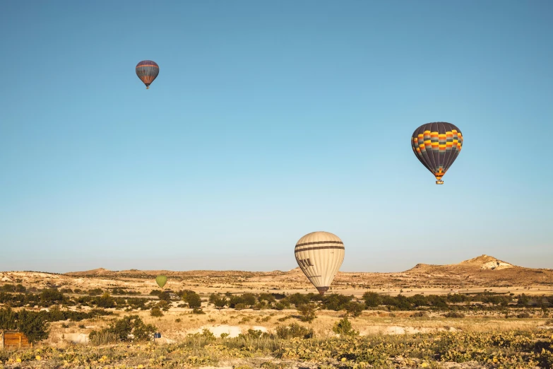 a couple of hot air balloons flying in the sky, by Daren Bader, pexels contest winner, egyptian landscape, three birds flying around it, cyprus, tatooine