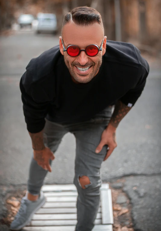 a man with red sunglasses is standing on a step, inspired by Michael Ray Charles, pexels contest winner, antipodeans, hairless, smiling down from above, background : diego fazio, round goggles