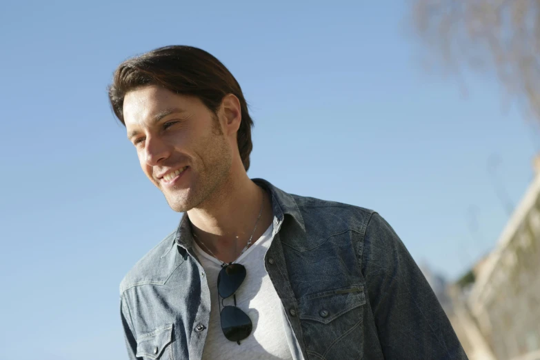 a man wearing a denim jacket and sunglasses, smiling man, caleb worcester, mid-shot of a hunky, profile image