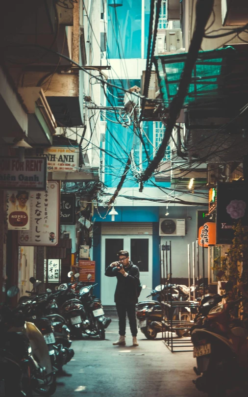 a man standing in the middle of a narrow alley, a photo, pexels contest winner, machines and wires everywhere, vietnam, teal aesthetic, promo image