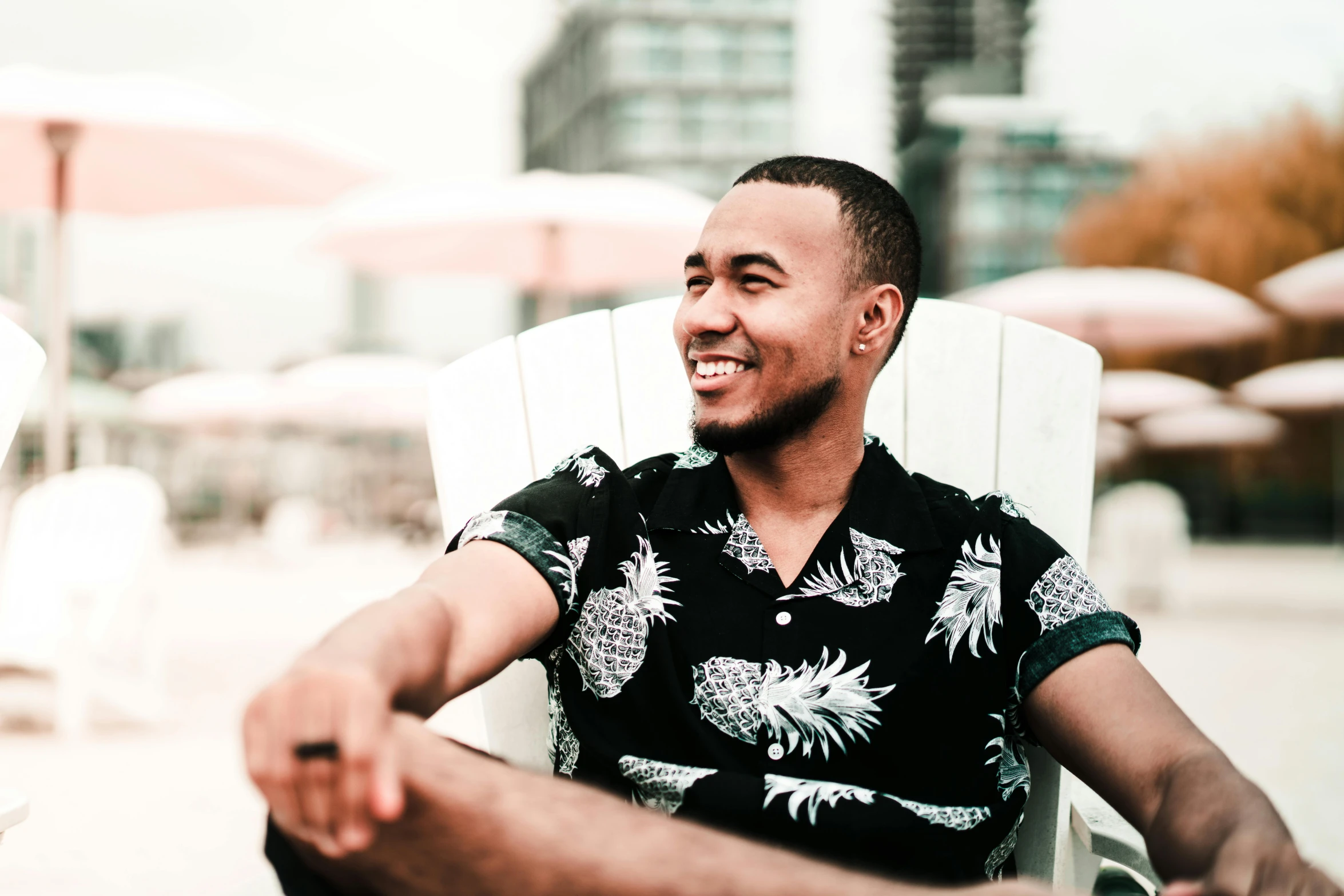 a man sitting on top of a white chair, pexels contest winner, hurufiyya, smiling :: attractive, with hawaiian shirt, african canadian, profile image