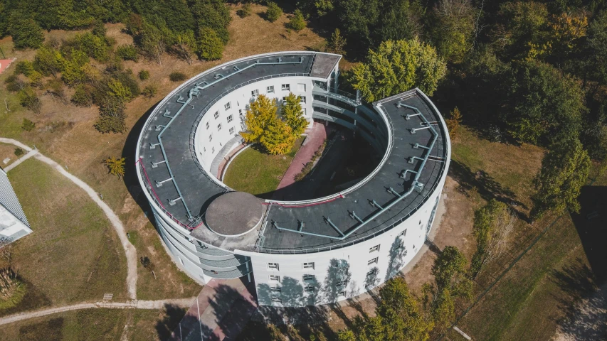 an aerial view of a circular building surrounded by trees, pexels contest winner, danube school, high angle security camera feed, bauhaus style, 15081959 21121991 01012000 4k, viewed from the ground