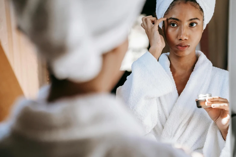 a woman in a bathrobe brushes her hair in front of a mirror, trending on pexels, mannerism, relaxed eyebrows, wearing white robes!, woman holding another woman, {perfect face}