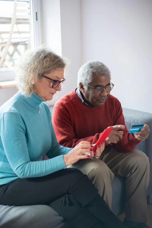 a man and woman sitting on a couch looking at a cell phone, card game, two aboriginal elders, holding a nintendo switch, inspect in inventory image