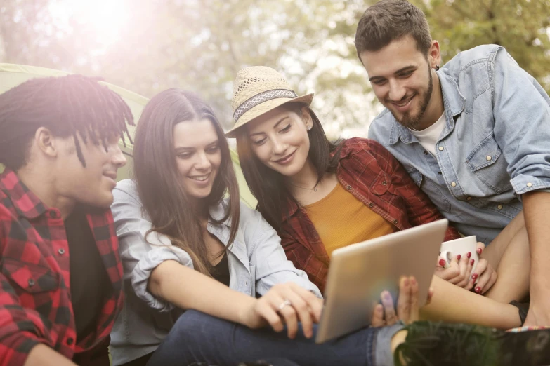 a group of young people sitting on top of a grass covered field, a picture, shutterstock, happening, using a magical tablet, sydney park, promotional image, tv still