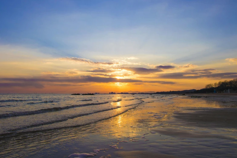 the sun is setting over the water on the beach, pexels contest winner, orange and blue sky, seaview, liquid gold, with a long