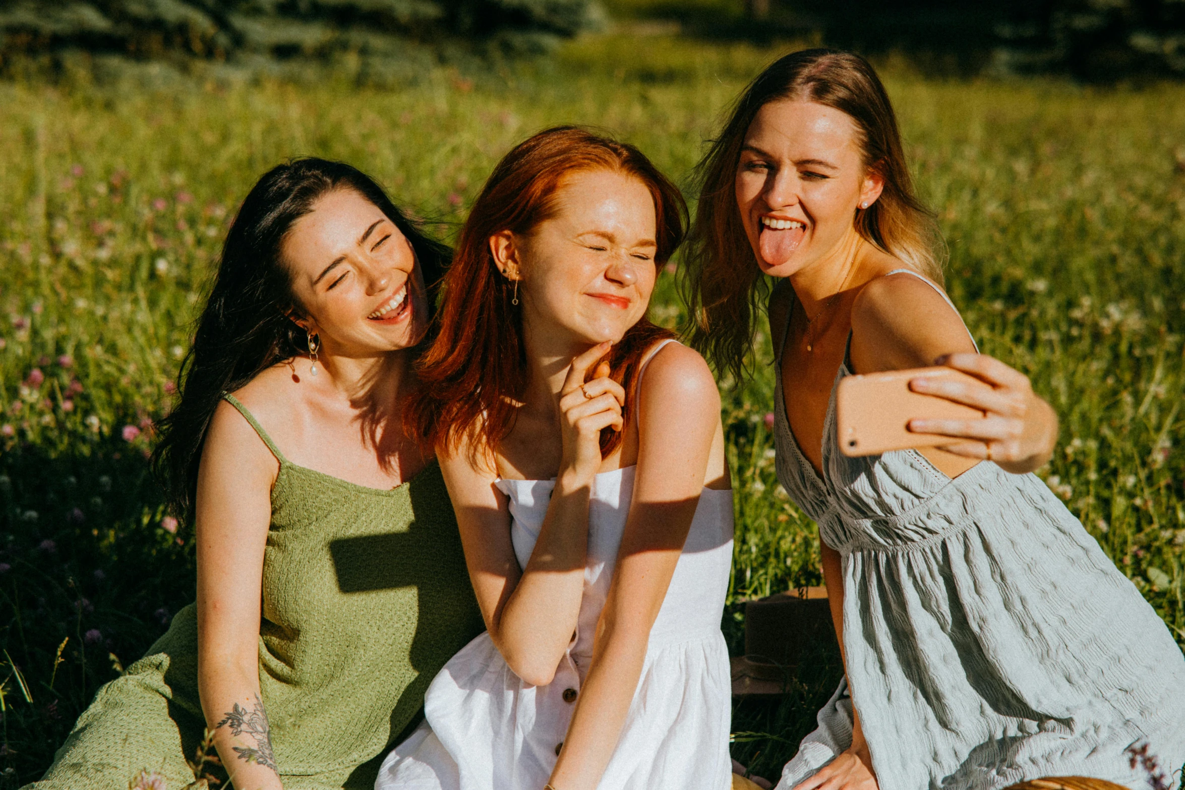 a group of women sitting on top of a lush green field, trending on pexels, happening, in love selfie, avatar image, redhead, making the best smug smile