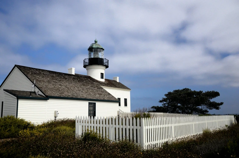 a white house sitting next to a white fence, by Carey Morris, pexels contest winner, lighthouse, square, california, preserved historical